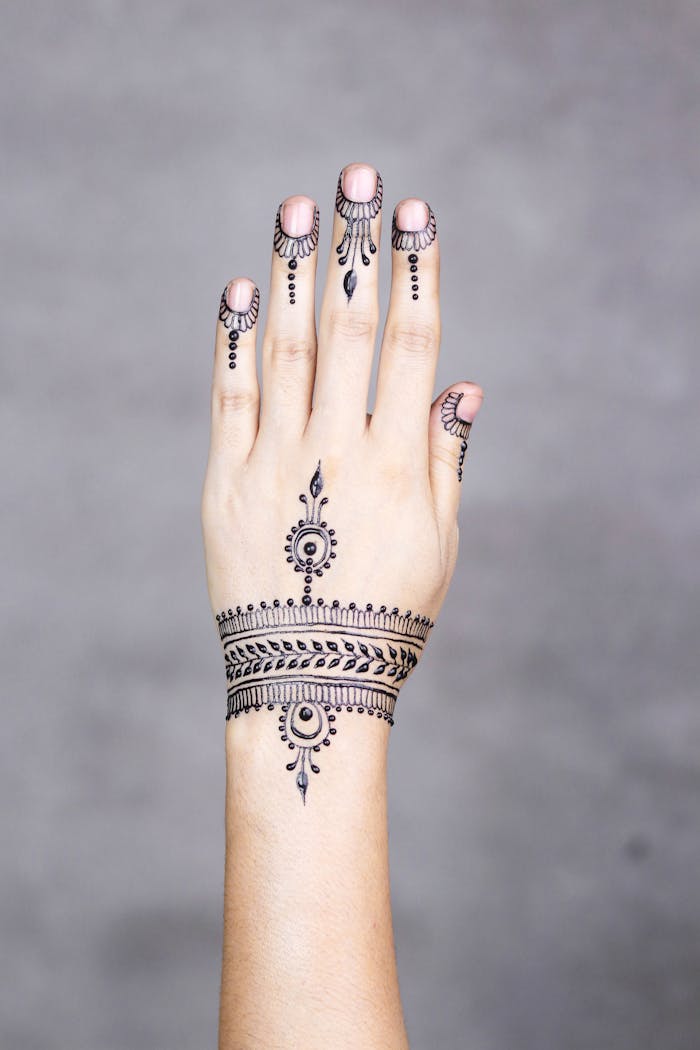 stats-img Close-up of a hand adorned with an intricate henna design, showcasing traditional art style on a minimalistic background.